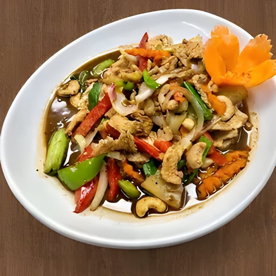 Angry Thai's cashew chicken stir-fry with colorful vegetables and a carved carrot garnish.