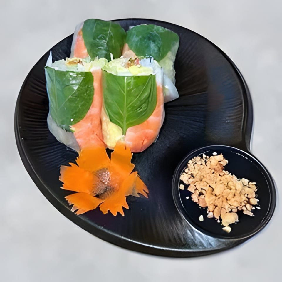 Three fresh spring rolls with shrimp and basil, served with a peanut dipping sauce and carrot garnish.